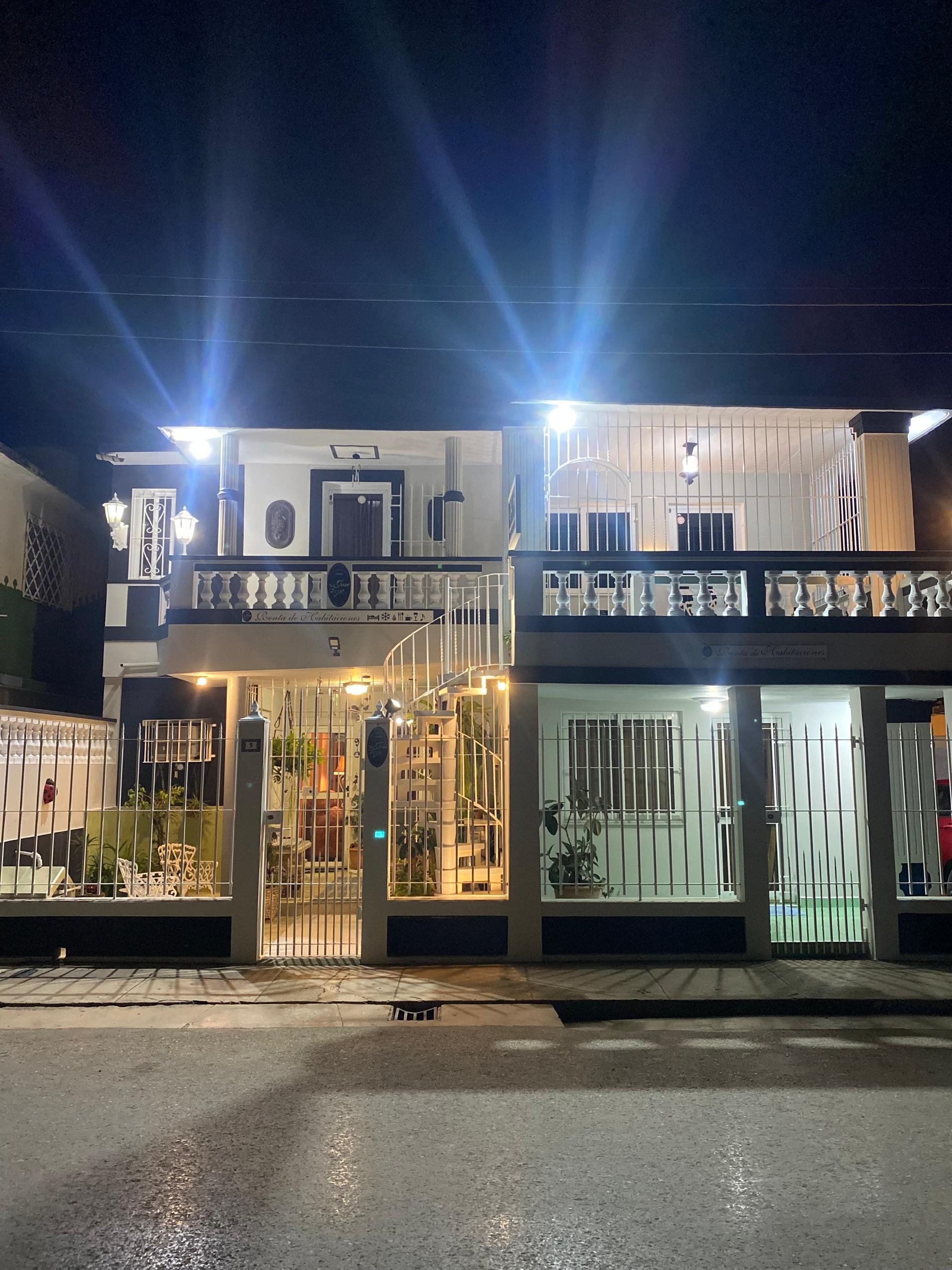 The two-storey Republican facade of Hostal Jose Cuba illuminated at night, in Cárdenas, with warm exterior lights