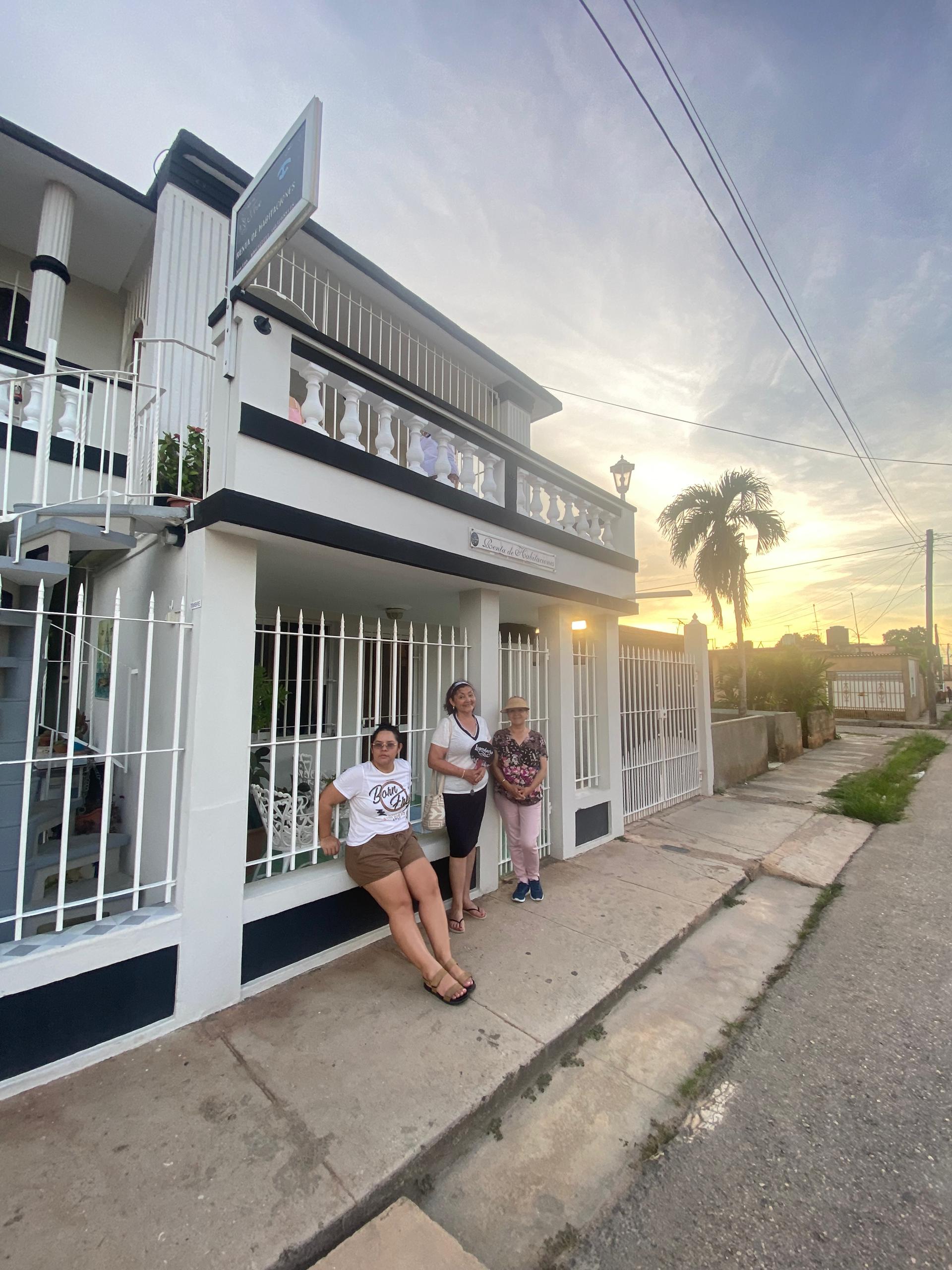Guests in front of the Hostal Jose Cuba facade at sunset with a palm tree