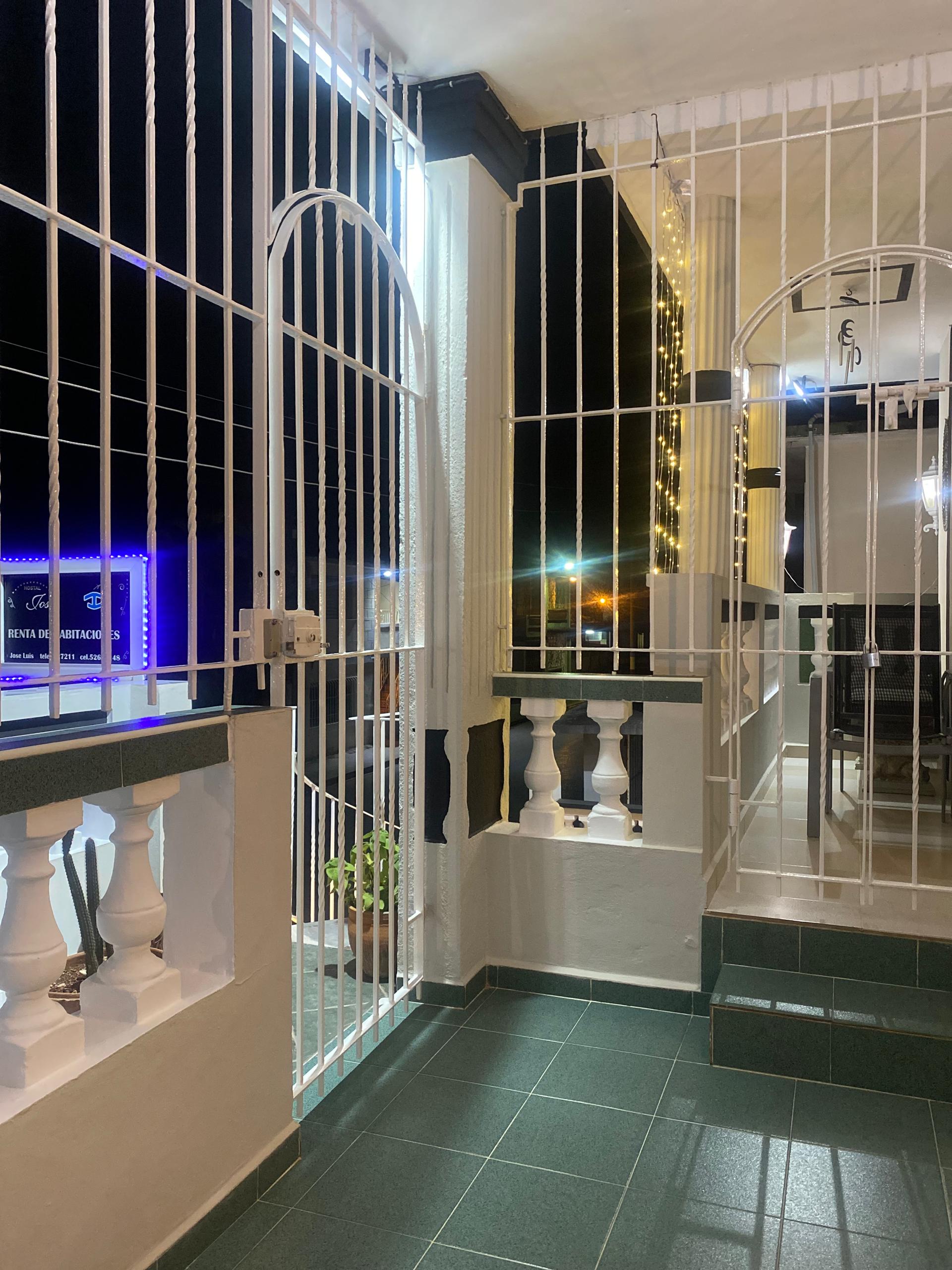 The interior gate of Hostal Jose Cuba at night, lit by cascading LED lights, opening onto the courtyard