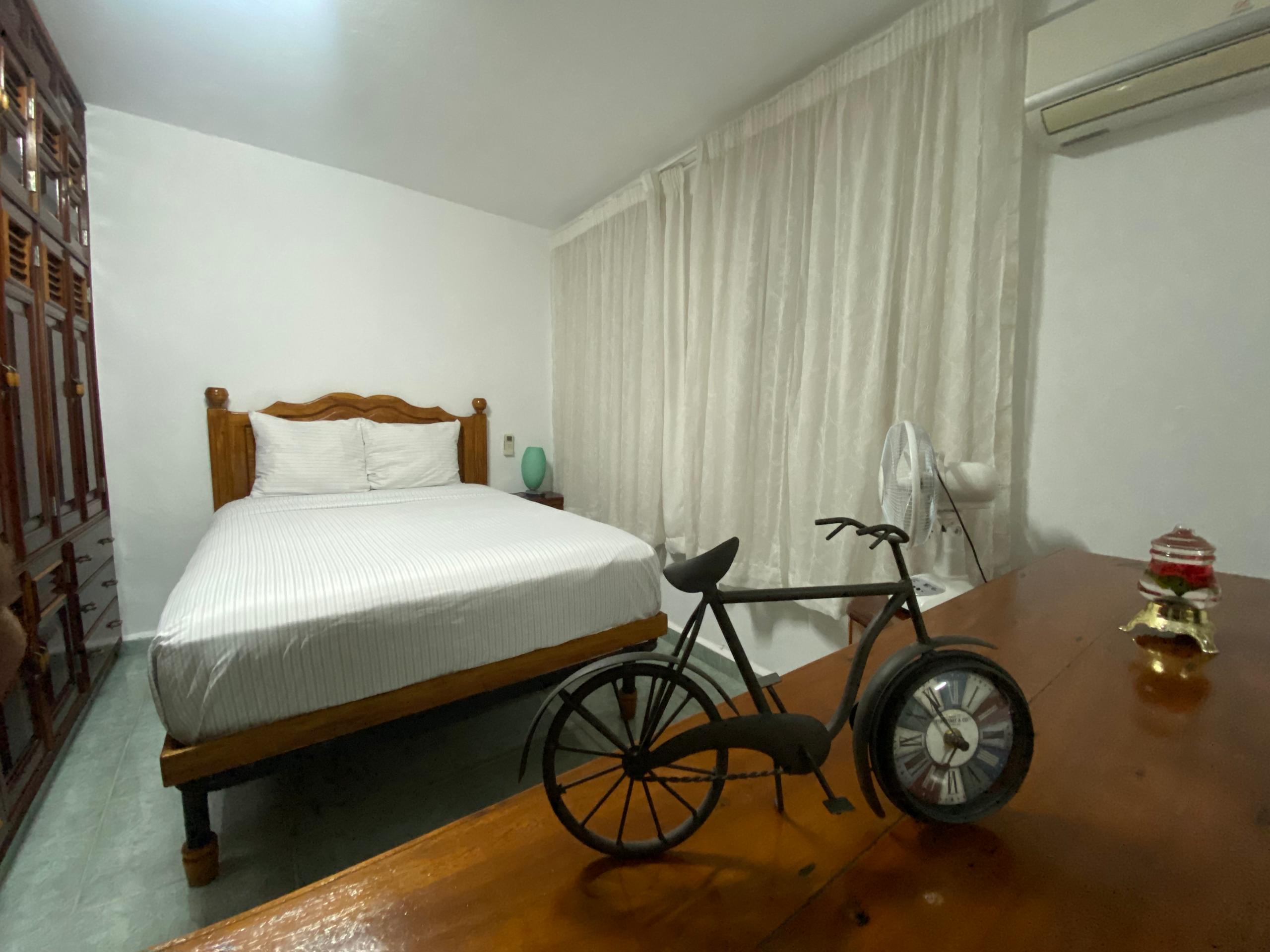 Bright room with white bedding and a decorative iron bicycle-clock on a side table