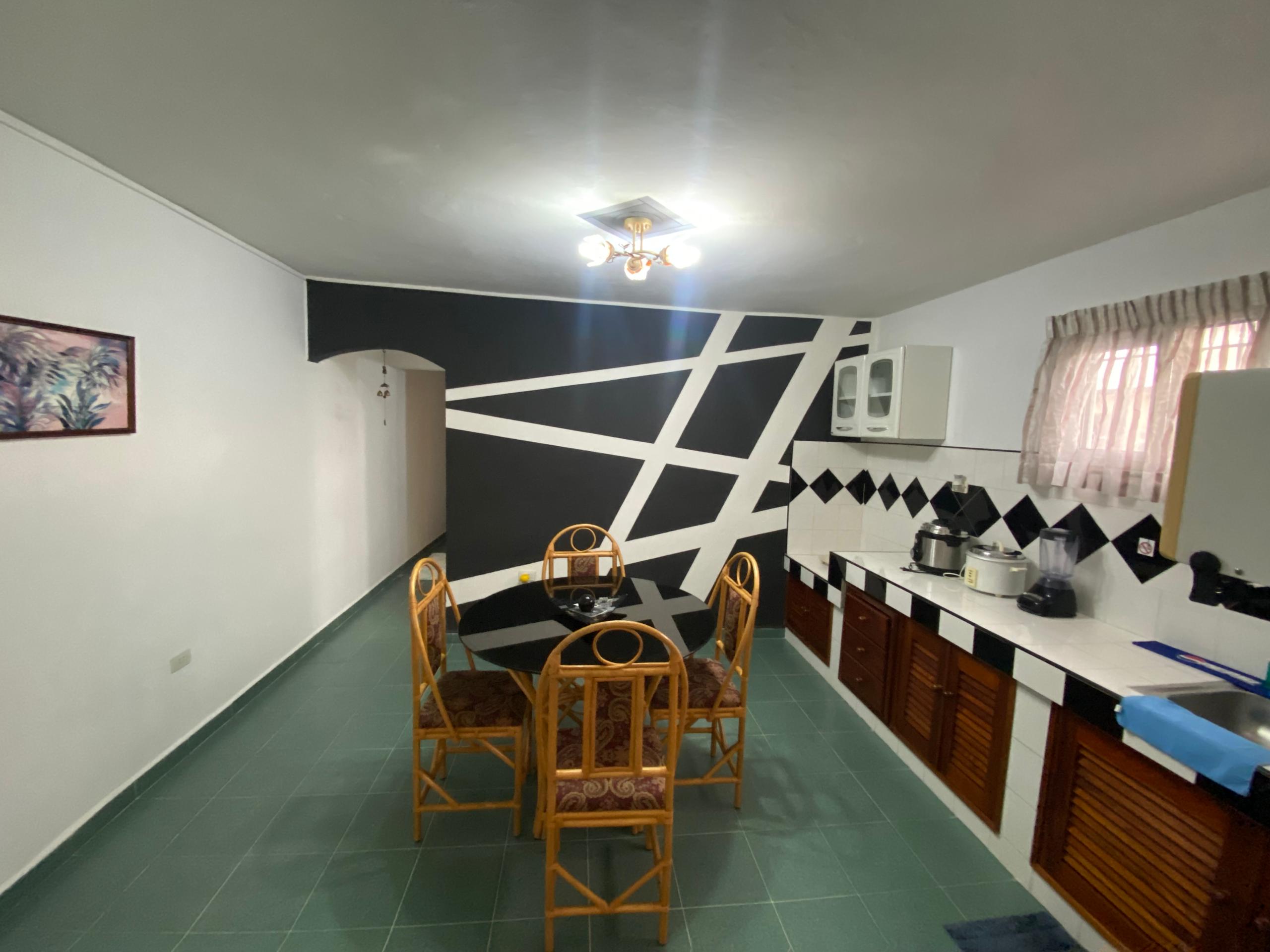 Dining room with glass-top table, woven chairs, black-and-white checkered tile and palm artwork